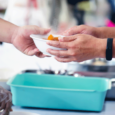 Closeup image of two people passing a bowl of food back and forth