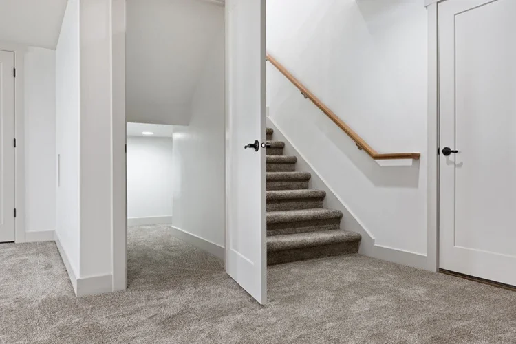 Basement area with new gray carpet and stairs leading up. Are Houses With Flood-Prone Basements More Expensive to Insure?