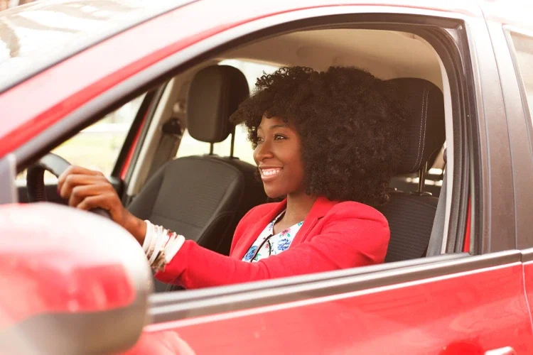 Young woman driving red car. 10 Insurance Myths Debunked. 