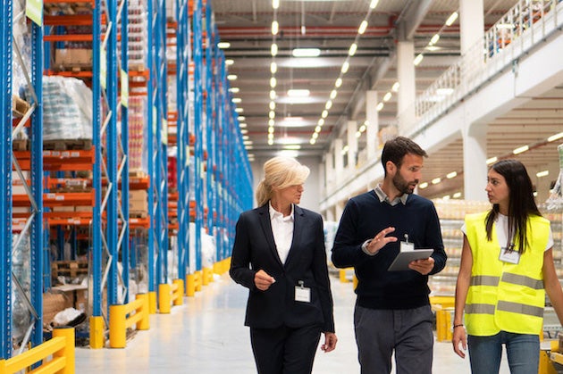 Management and employee walking through a warehouse and talking about EPLI Coverage