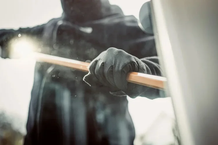 Burglar breaking into apartment with a crowbar. In Mississippi, Does Renters Insurance Cover Property Crimes, Too?