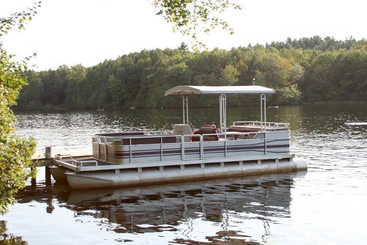 A pontoon boat moored to a dock. The most expensive boats to insure in Illinois.