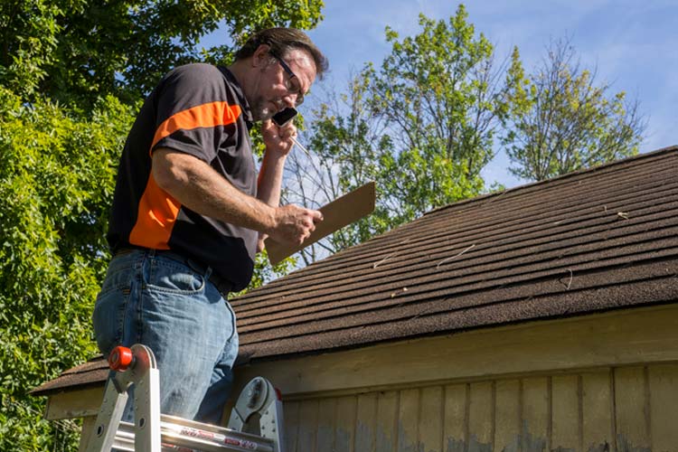 Roofing contractor on ladder figuring out hail damage repair costs for customer. How to protect yourself from roofing insurance scams in Kentucky.