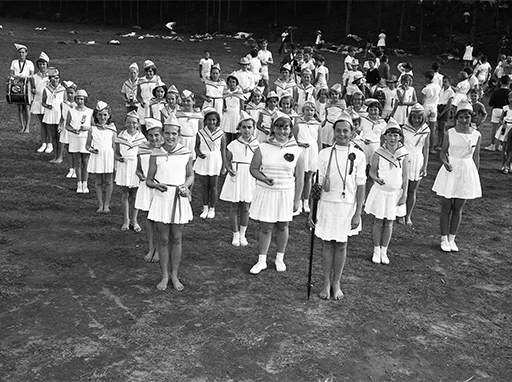 Thistle Pipe Band on the oval at Woombye State School during the Woombye State School's sports day, July 1957.
