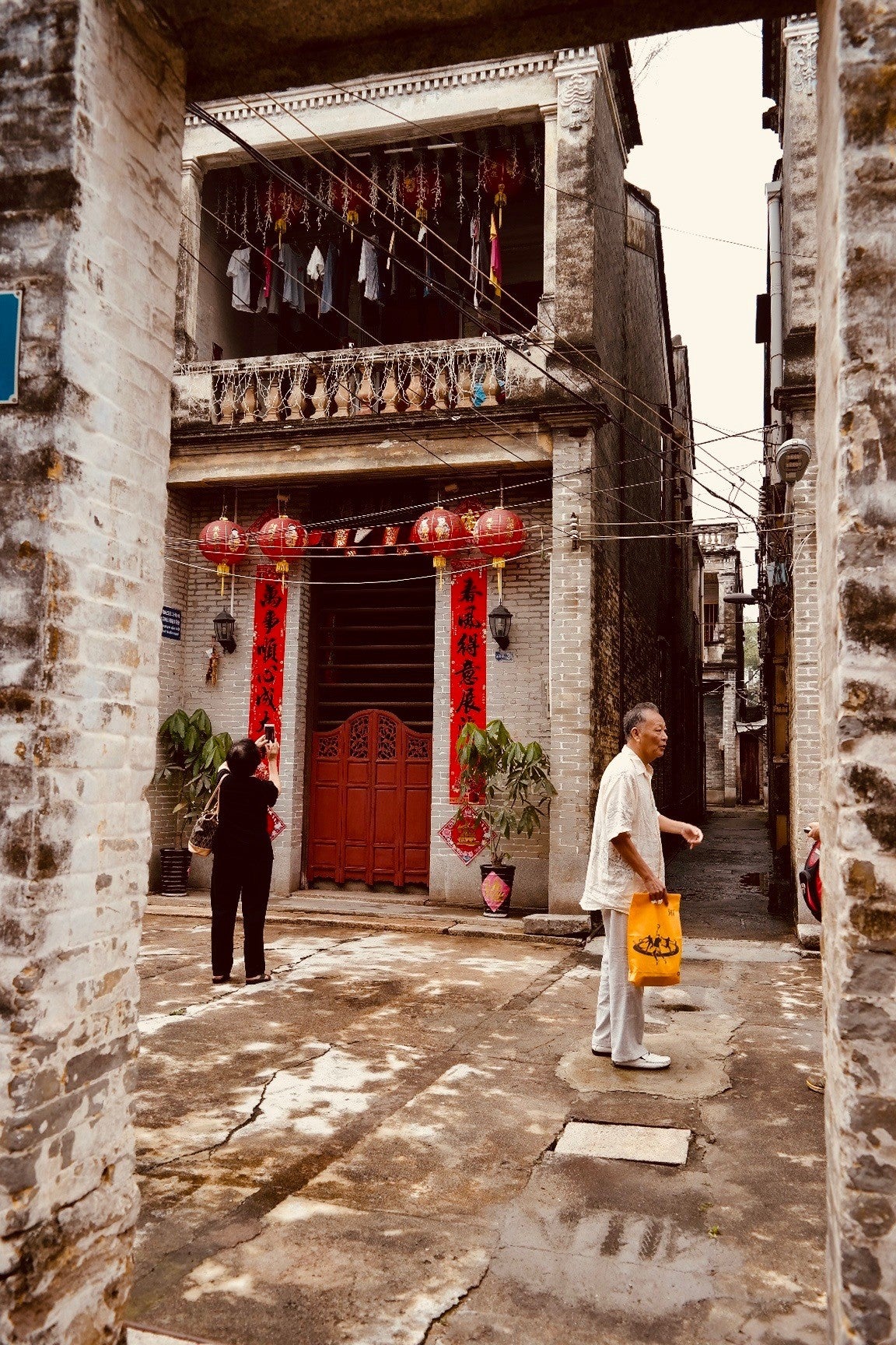 通过入口看到的前排房屋。照片中的男子是甘建波，他曾是中山市政府文物局的文物专家。