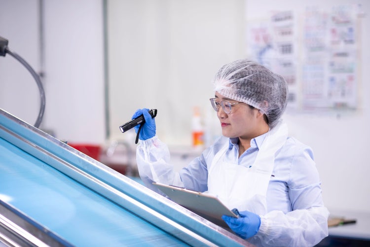 Employee performing visual inspection with flashlight and notebook