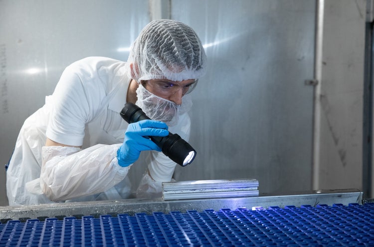 Man in PPE performing visual inspection with a flashlight
