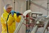 Man in PPE rinsing dirty conveyor