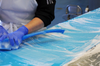 Hands with blue brush, scrubbing conveyor belt during wet cleaning