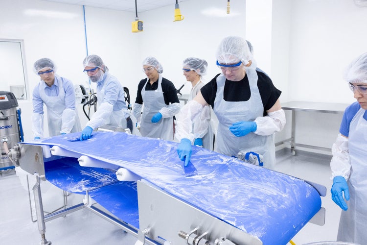 Participants practice cleaning techniques on a food processing conveyor during training at CFS Institute North America.