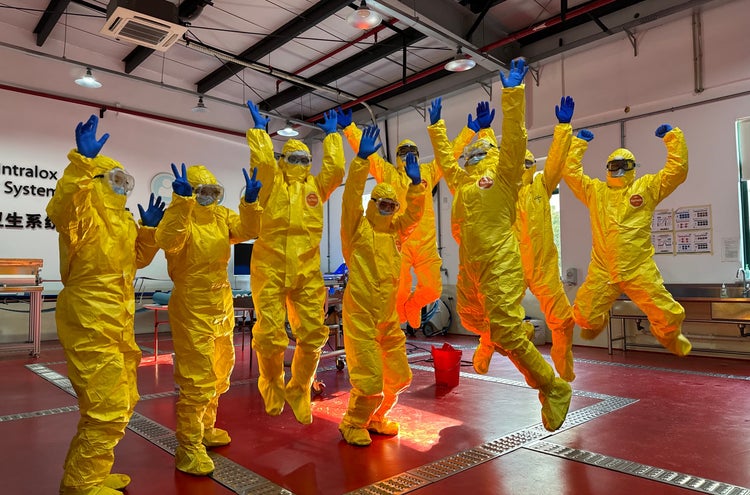 Participants in yellow PPE jumping in China Sanitation Essentials Training