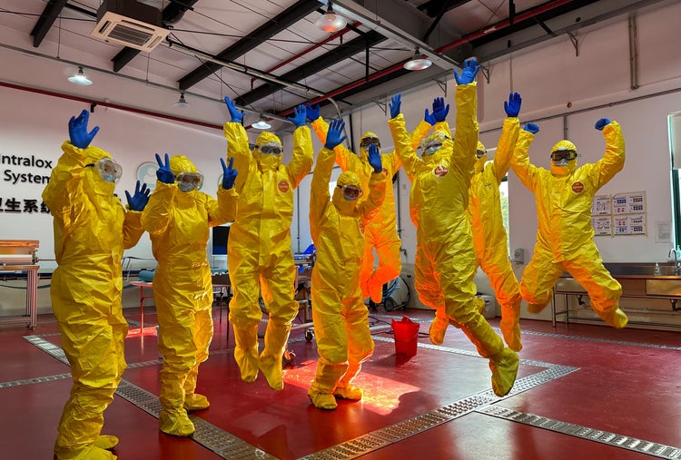 Participants in yellow PPE jumping in China Sanitation Essentials Training