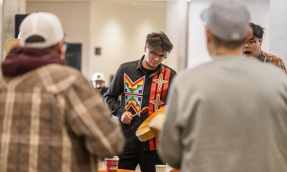 A man playing drums with other people around him