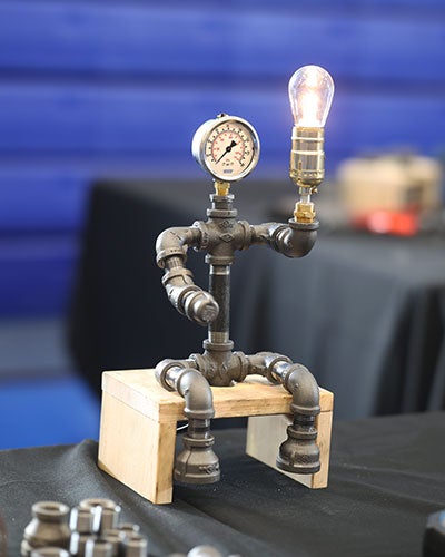 A pipe sculpture with a gauge and a light bulb