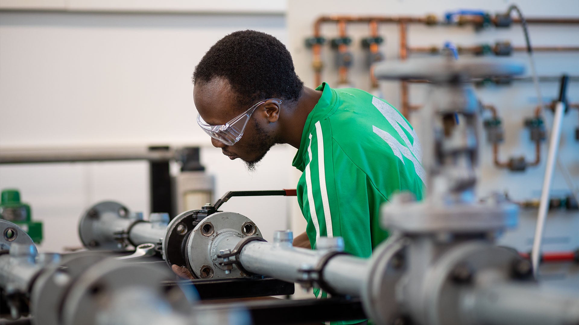A man wearing safety glasses works on a pipeline.