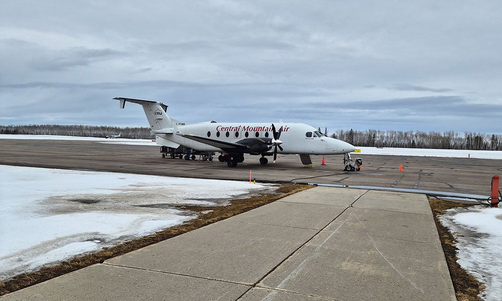 Small passenger airplane labeled “Central Mountain Air” parked on a snowy airport tarmac with overcast skies and equipment nearby.