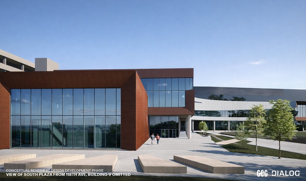 Modern, multi-storey institutional building with a mix of glass, white, and red-brown exterior panels, featuring large angular overhangs and expansive windows. The view shows the south plaza from a street entrance, with a sidewalk, landscaped trees and a few pedestrians nearby.
