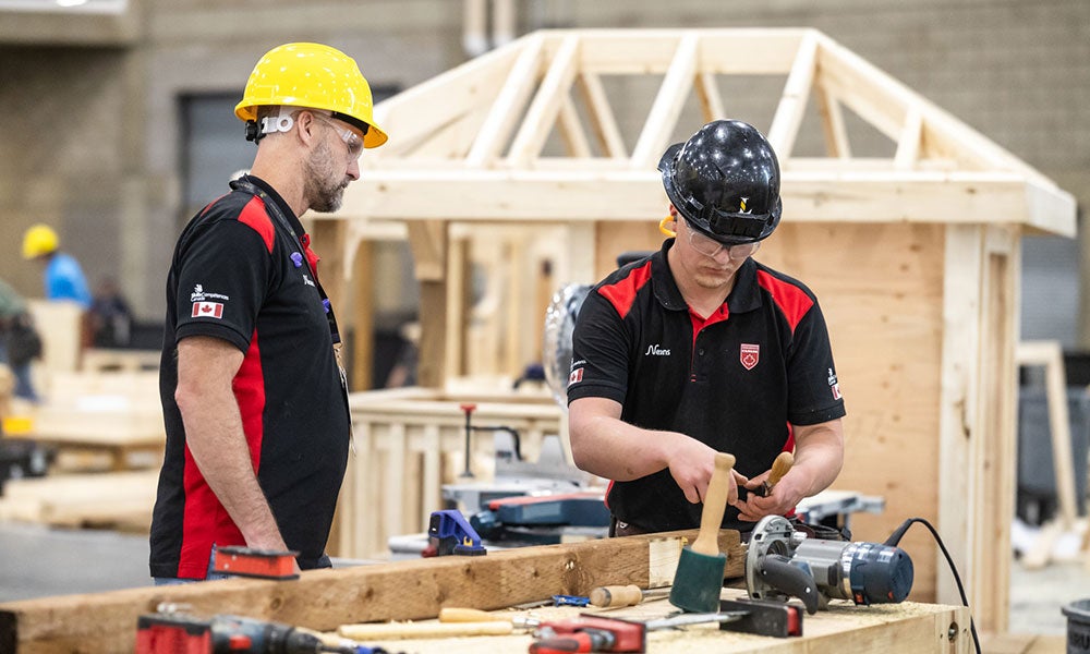 A group of men wearing hard hats and working on wood