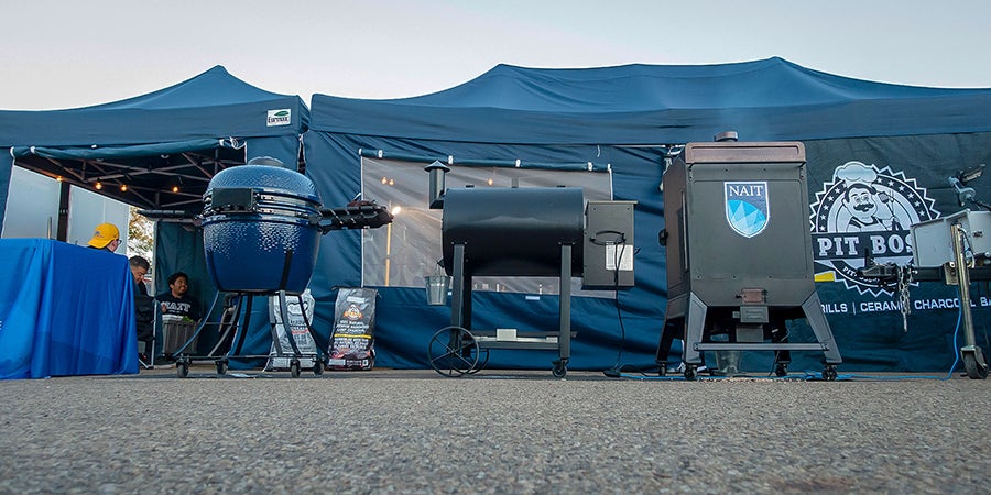 A barbecue grills and smokers in front of a tent