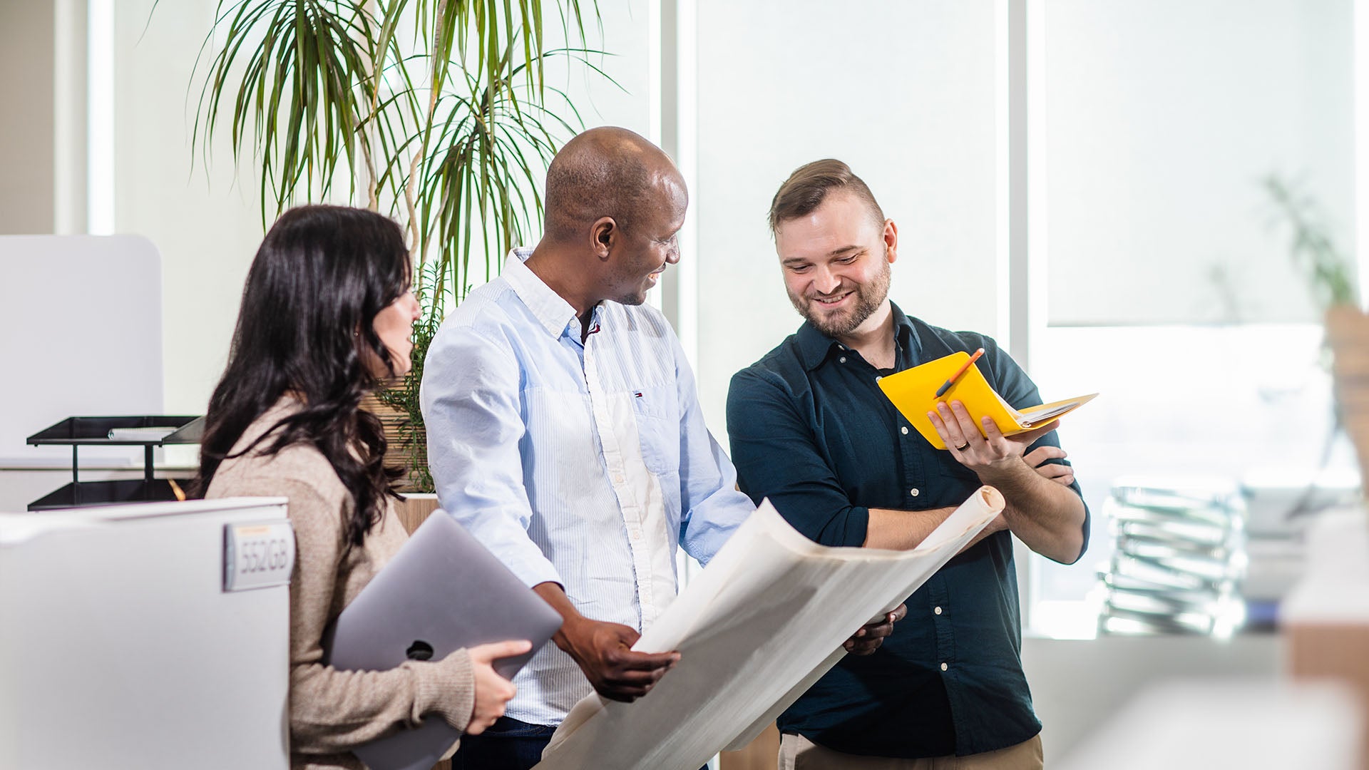 Three people in a discussion in an office setting.