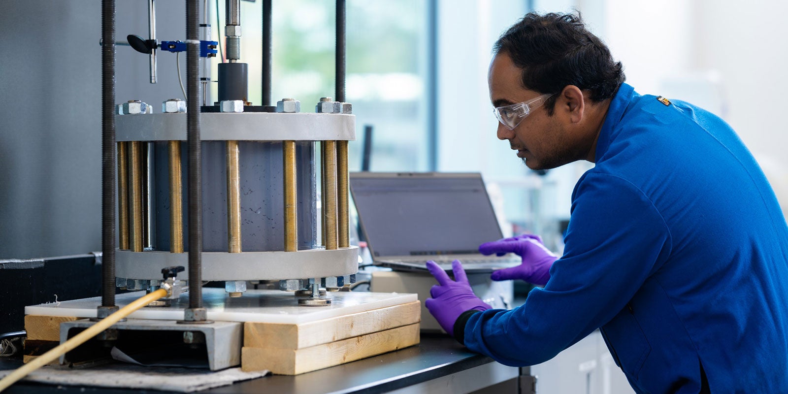 A man wearing gloves and working on a laptop A man wearing gloves and working on a laptop