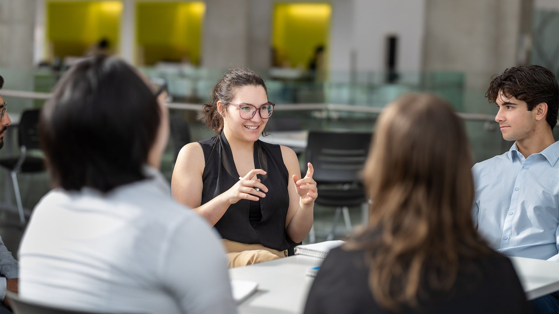 A group of business administration students sitting at a table having a discussion.