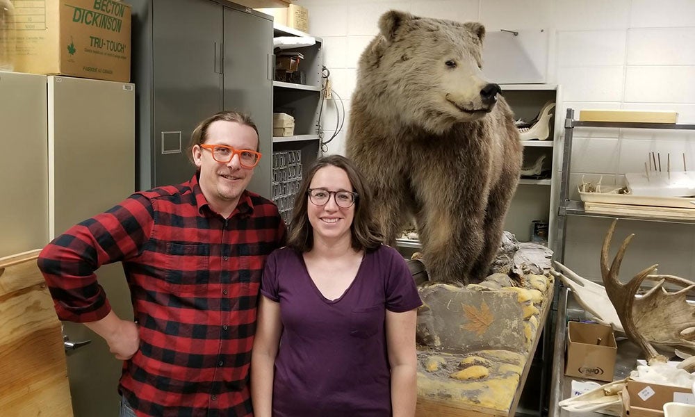 A man and woman posing for a picture with a bear