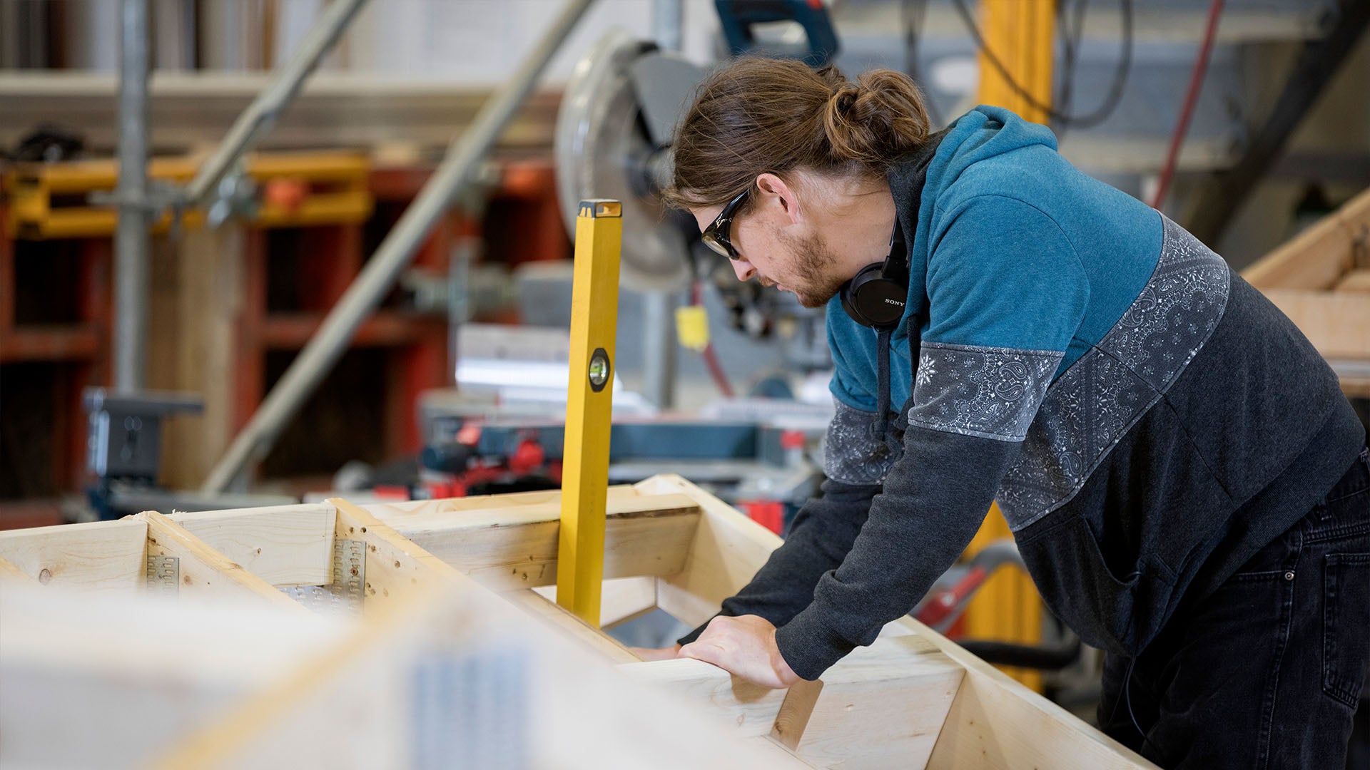 A carpenter leans over and inspects framing. A carpenter leans over and inspects framing.