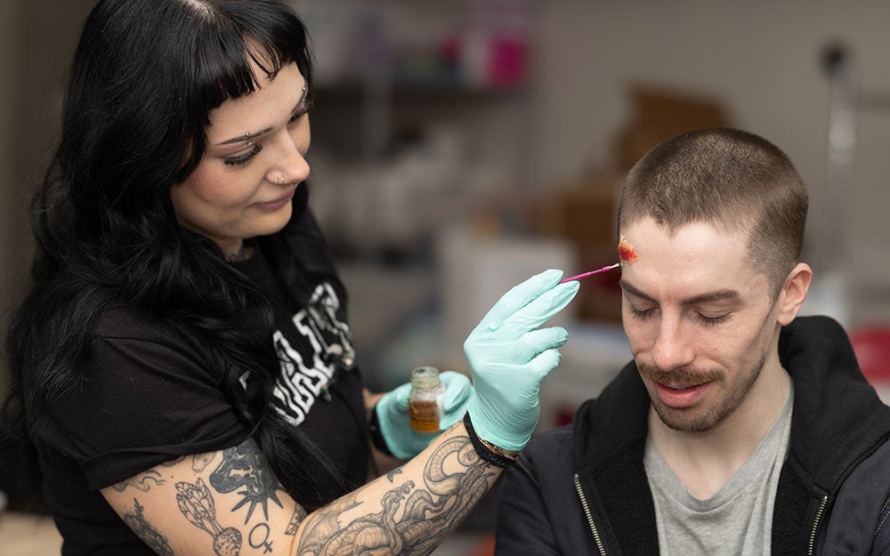 A woman painting a man's forehead