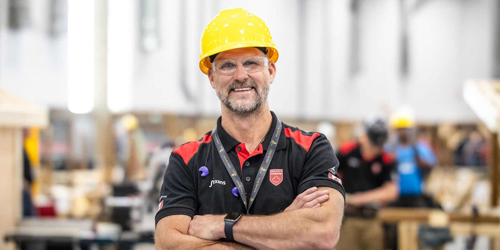 A man wearing a yellow hard hat and black polo shirt A man wearing a yellow hard hat and black polo shirt
