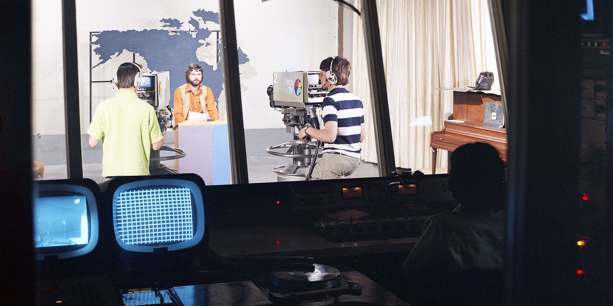 A group of people in a room with a large camera A group of people in a room with a large camera