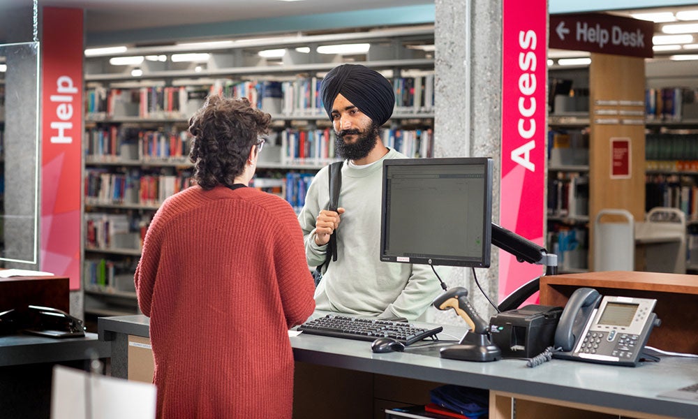 A man standing at a desk with a computer in front of a woman