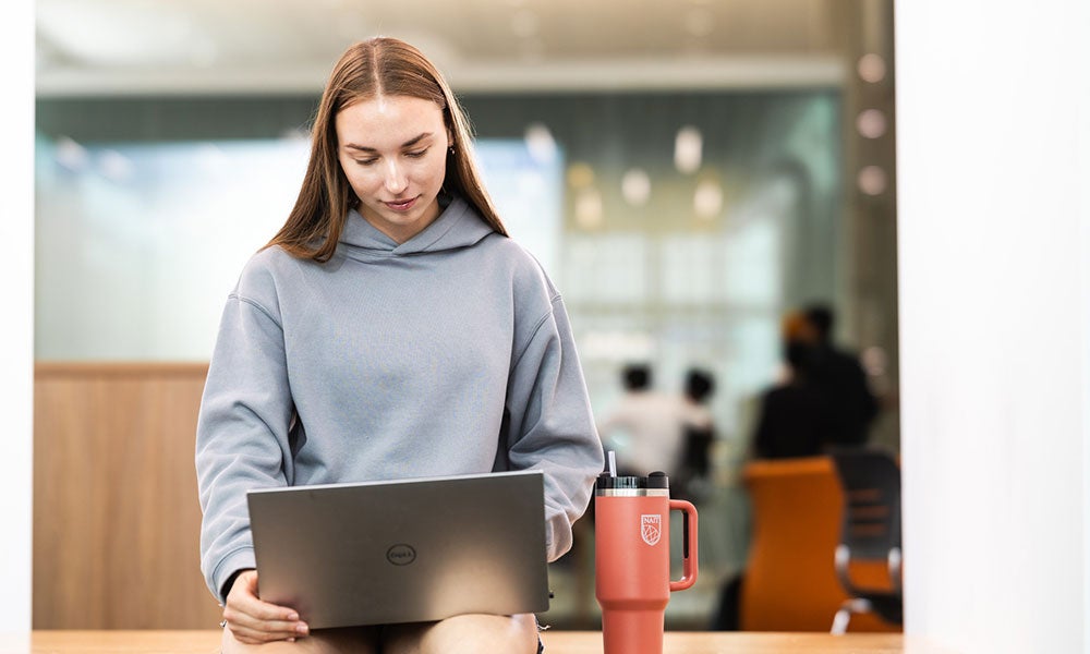 A woman sitting on a table with a laptop and a mug