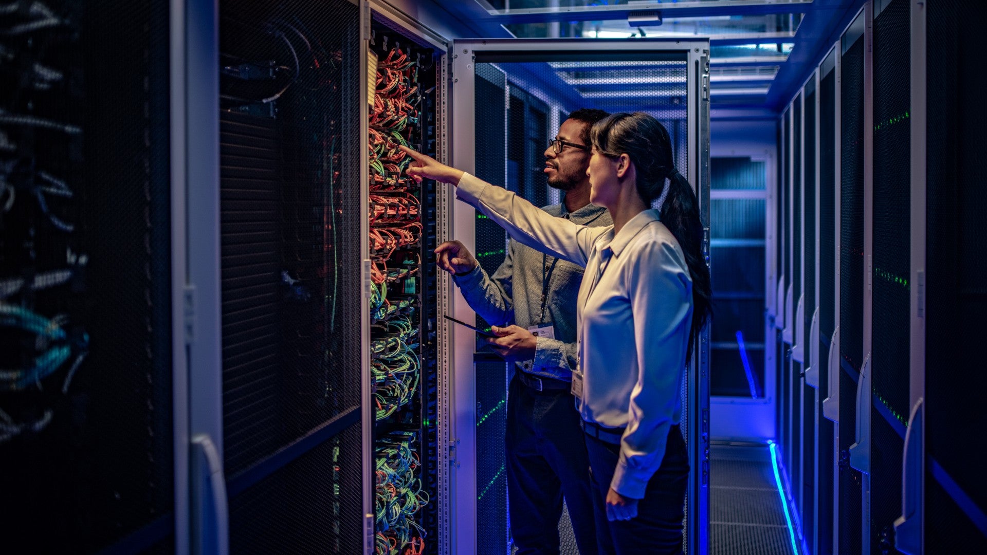 A man and woman standing next to a computer