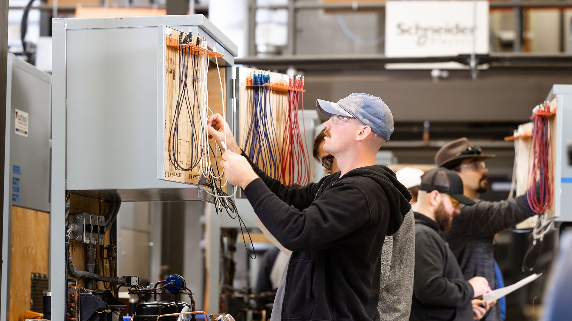 A refrigeration and air conditioning student connects colored test leads inside an electrical training cabinet to measure or troubleshoot a system circuit. A refrigeration and air conditioning student connects colored test leads inside an electrical training cabinet to measure or troubleshoot a system circuit.