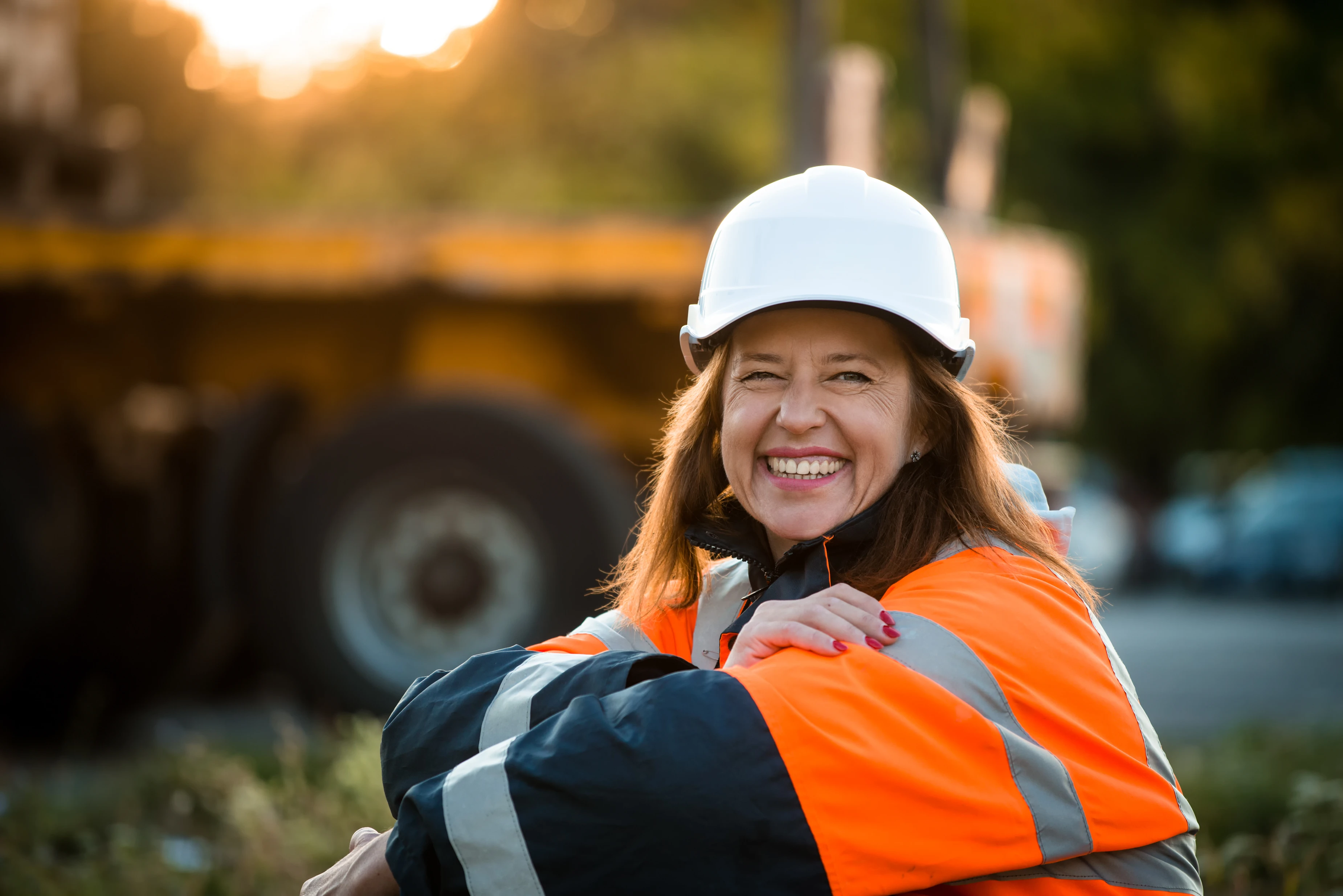 Senior woman engineer wearing protective wear in work - outdoor at sunset.