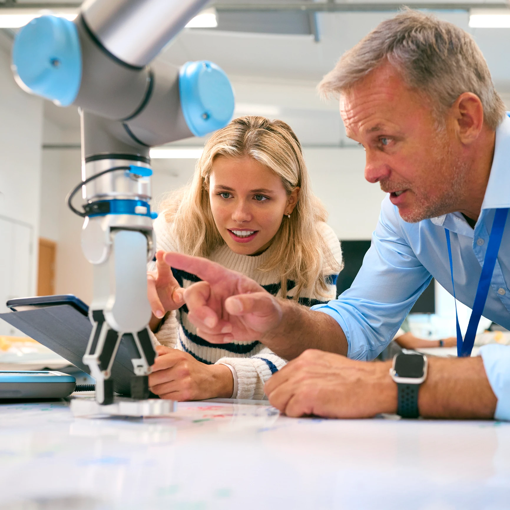 Female engineering apprentice wearing a jumper in a lab with employer teaching