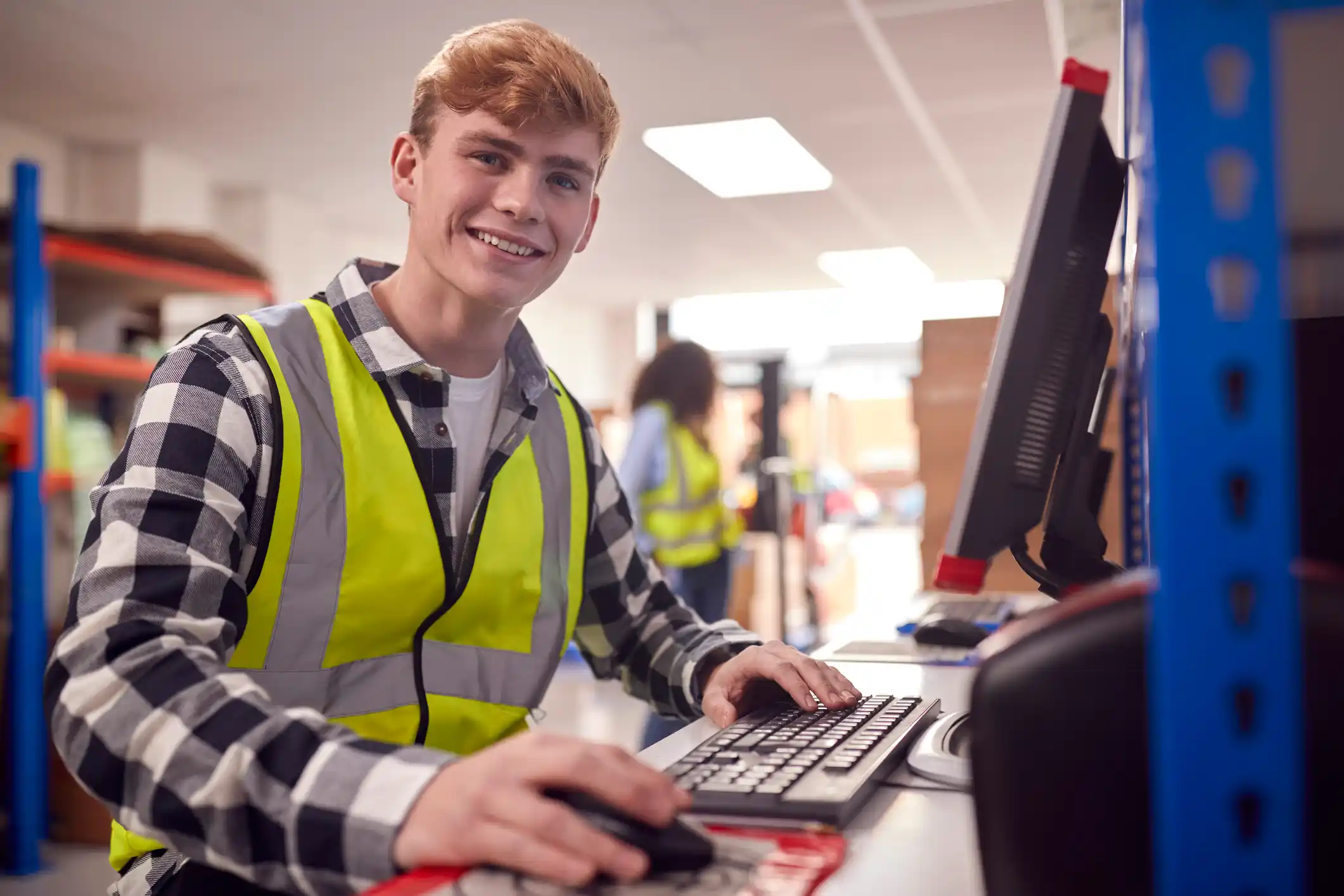 Engineering apprentice in a high vis jacket at a lab working on a computer