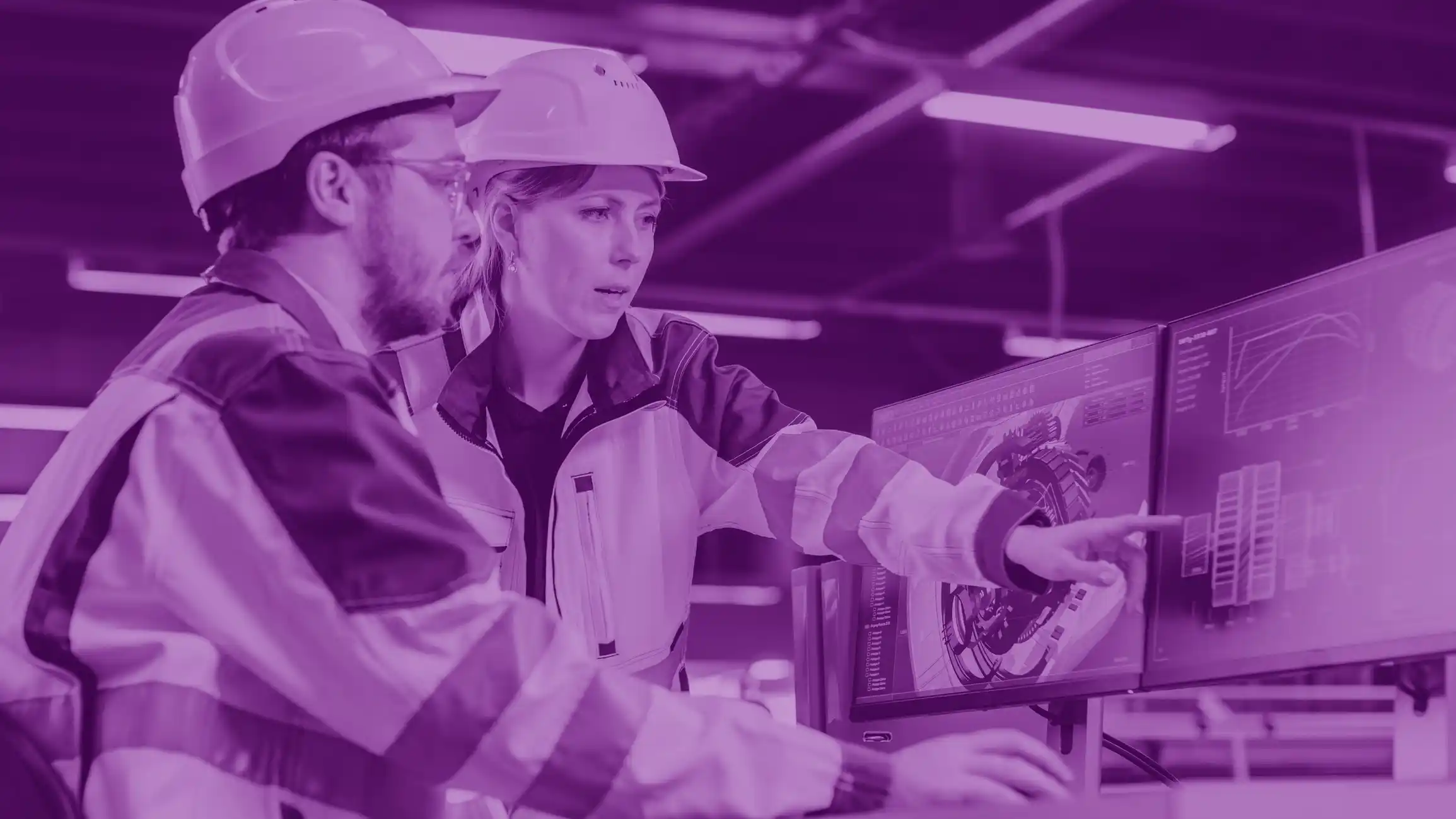 Two engineers in an office in protective gear working together on a project