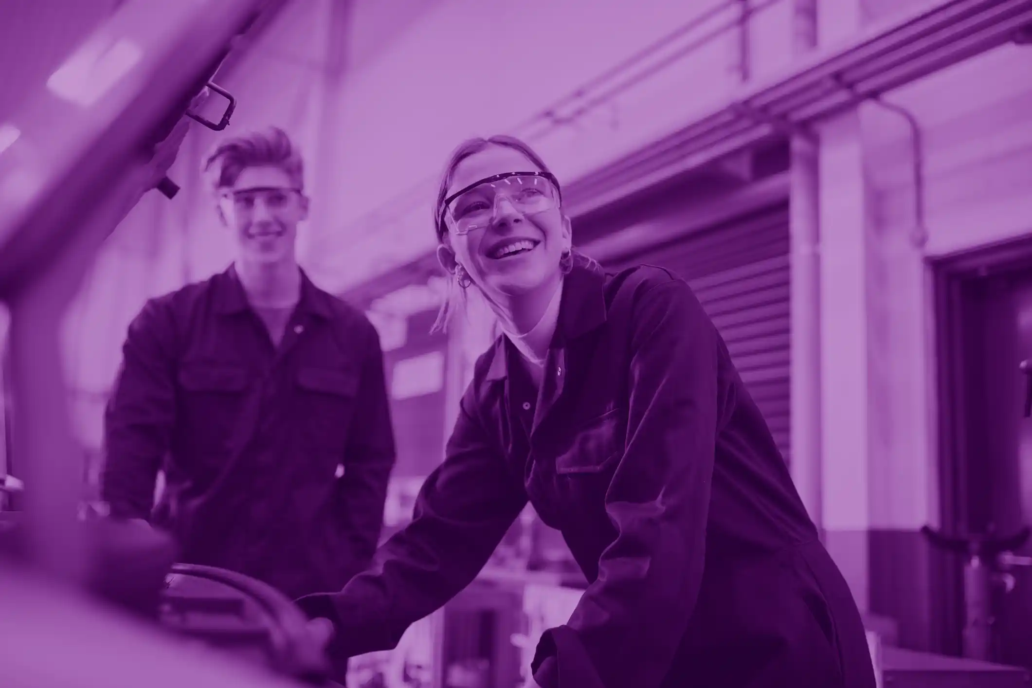 Male And Female Students Looking At Car Engine On Auto Mechanic Apprenticeship Course At College in purple tint