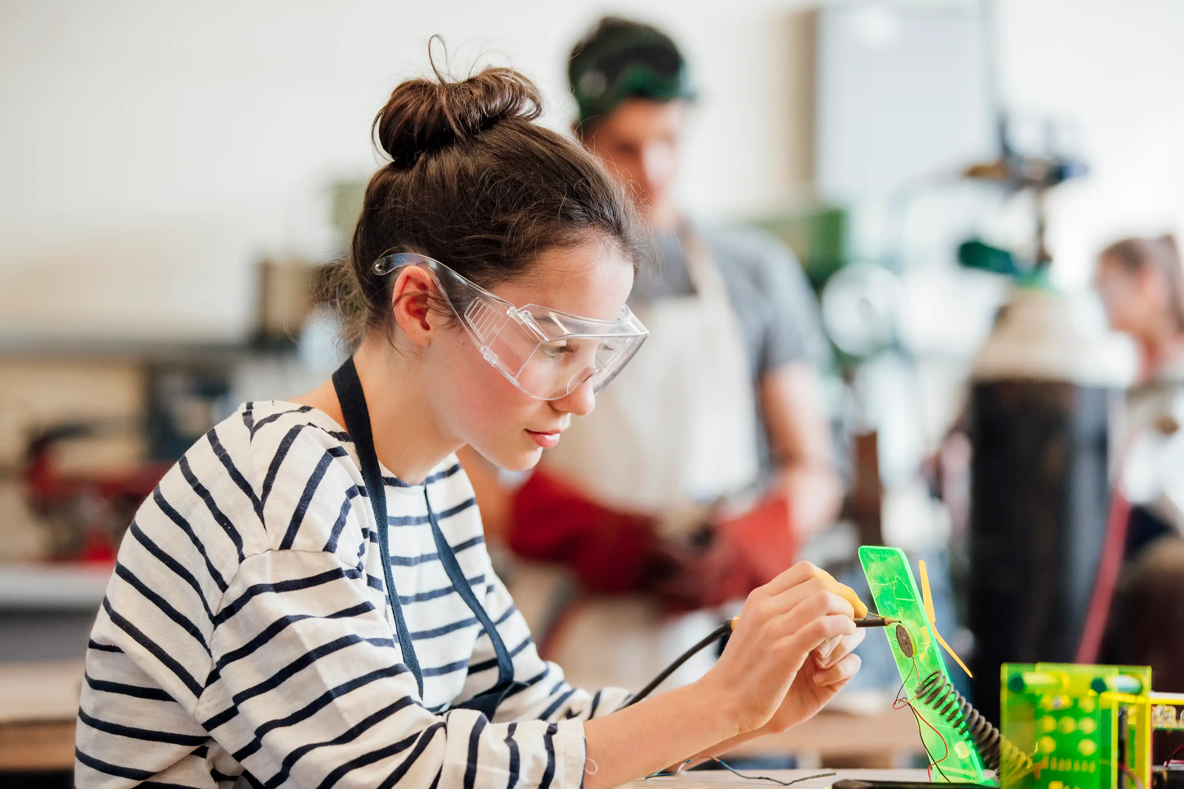 A child working with AI technology wearing safety goggles.