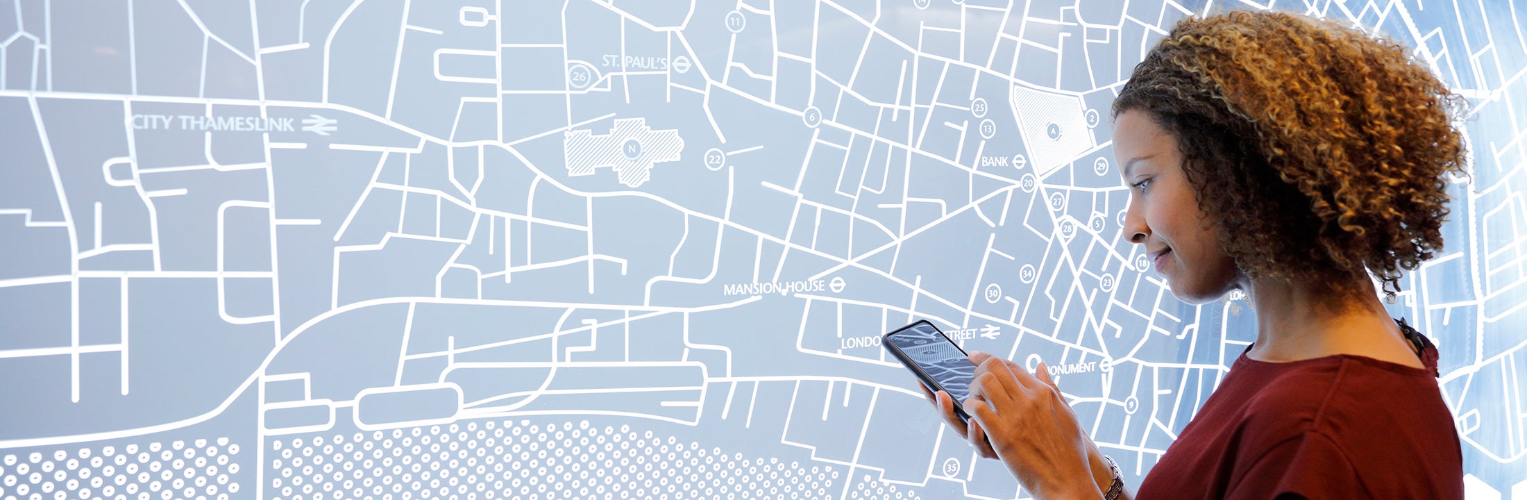 Woman using her phone in front of a map