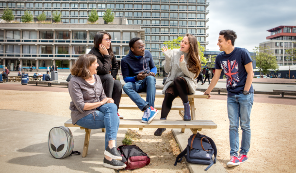 Een groep studenten op een bankje op het campusplein