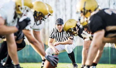 Referee looks at footballers on footballfield