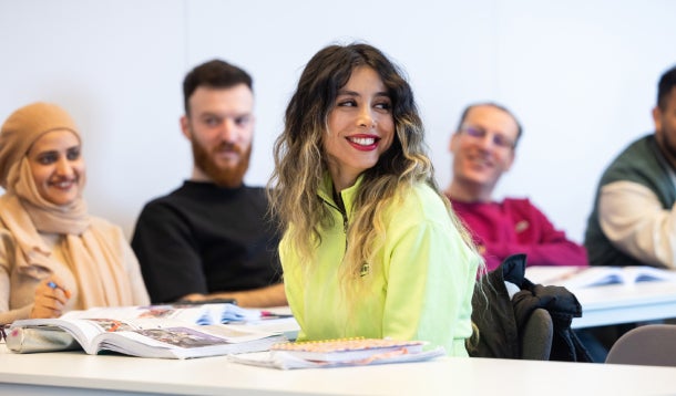 Een glimlachende vrouw met een groep medestudenten achter haar