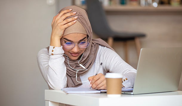 Student writing behind a laptop