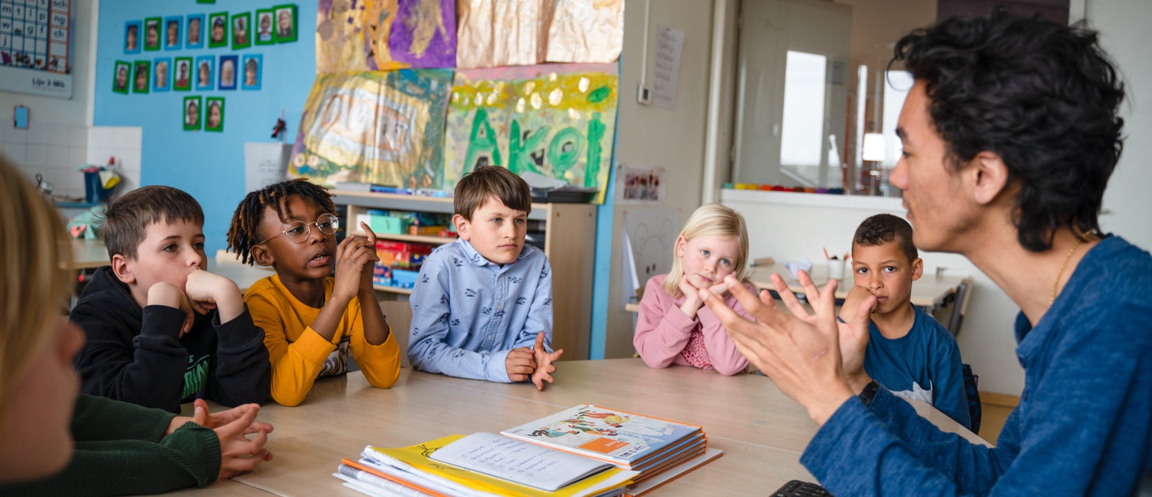 Teacher in a conversation with a group of primary school children (sitting around a table)