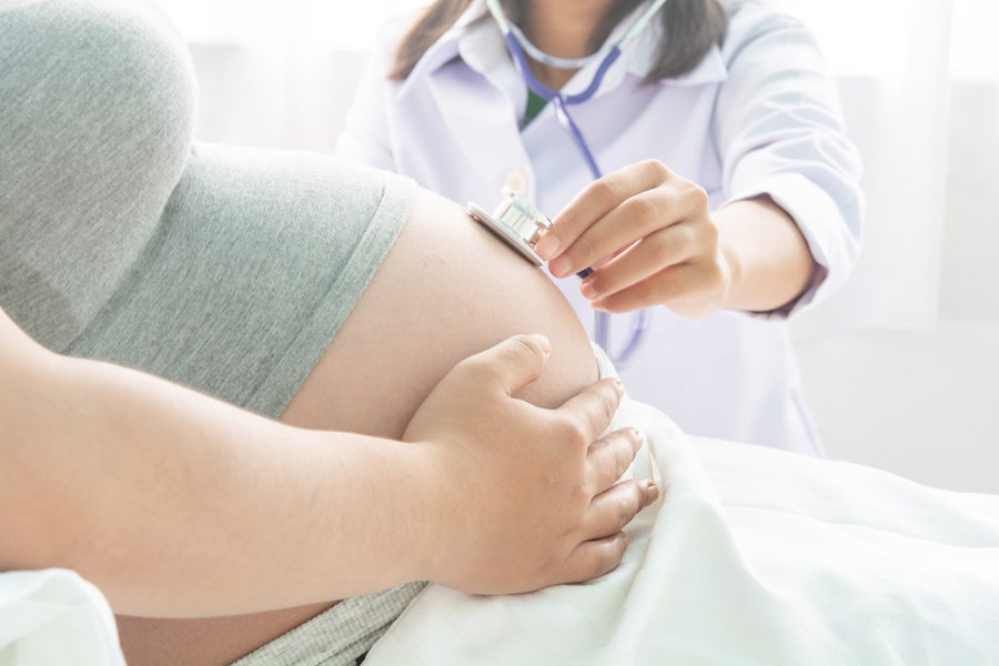 Doctor examines pregnant woman's belly with a stethoscope. 