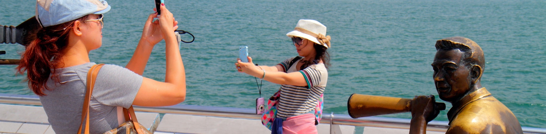 Two women making pictures by the sea