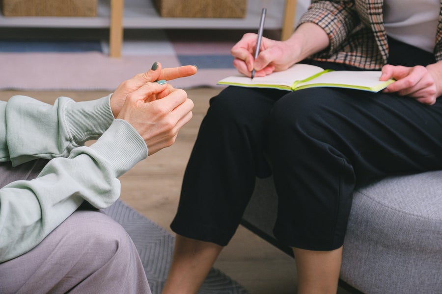 Two people are talking, one is taking notes.